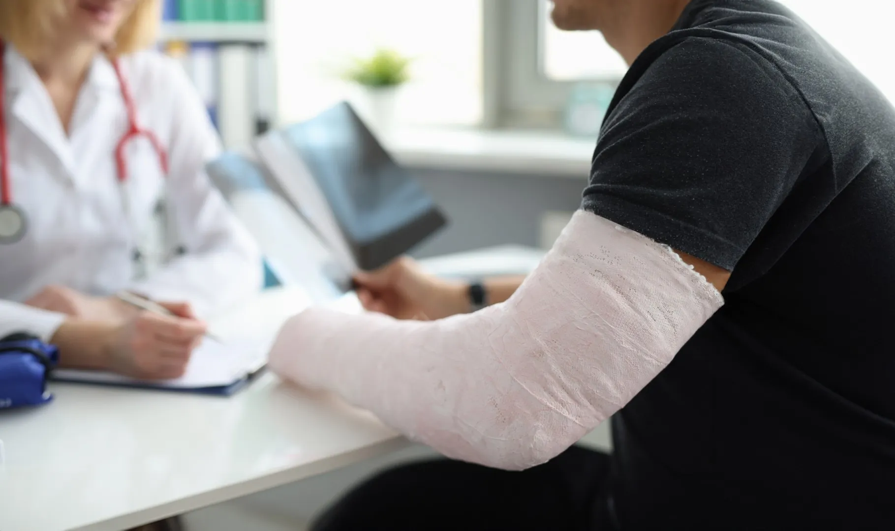Injured worker with arm cast meeting doctor, representing treatment and documentation used in California workers compensation claims.