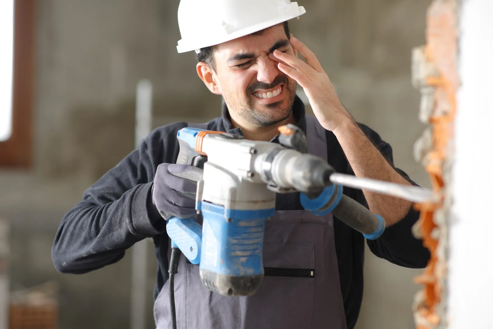 Construction worker rubbing injured eye while using power tool, representing workplace eye injury claims under California workers compensation law.
