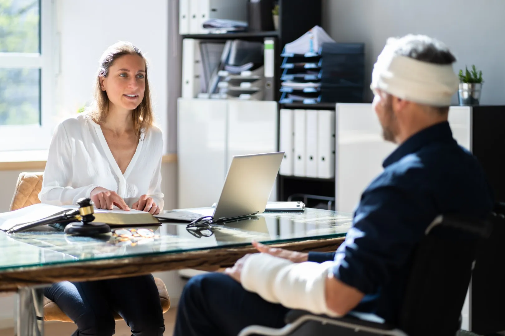 Injured worker with head and arm bandage meeting legal professional, representing claim guidance after a serious workplace accident in California.