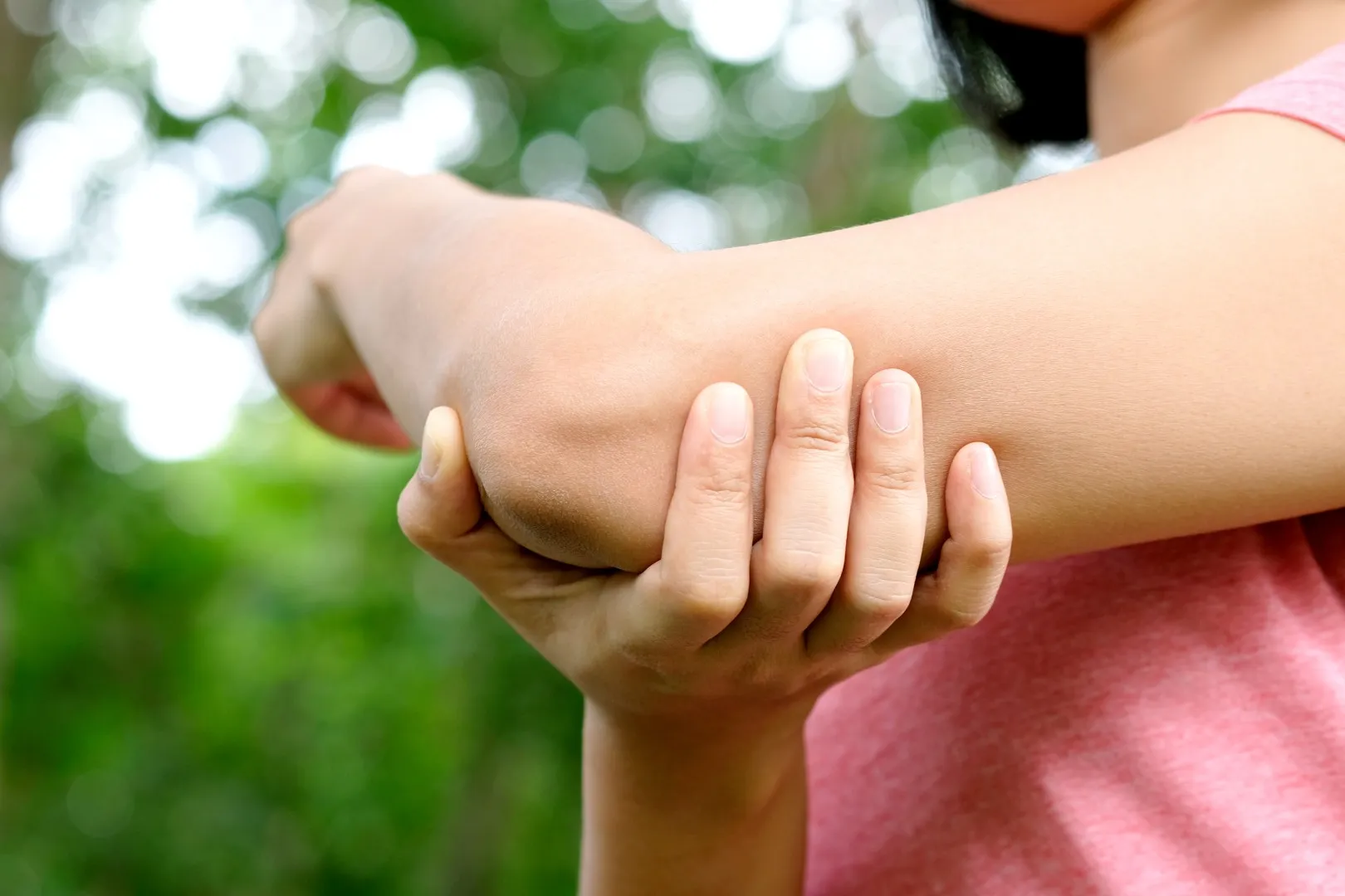 Person holding elbow in pain after possible workplace injury, highlighting need for a neck and back injury lawyer or workers compensation attorney in California.