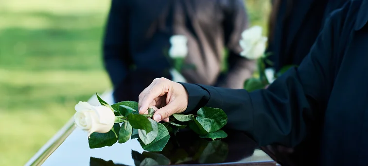 White rose placed on casket during memorial, representing wrongful death claims and California workers compensation death benefits.