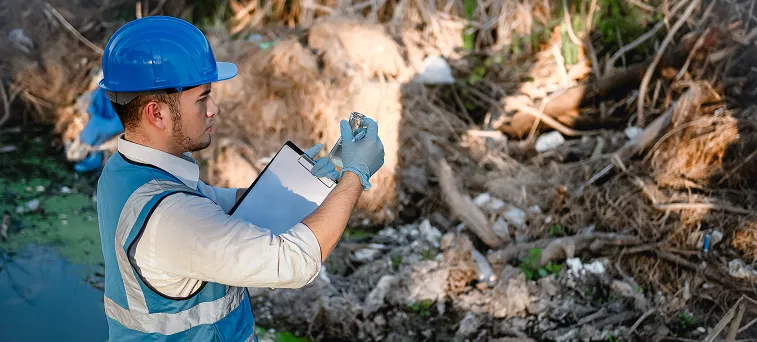 Worker collecting environmental samples near hazardous area, representing occupational exposure and environmental injury risks in California.