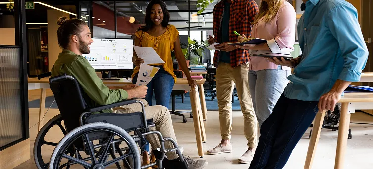 Employee using wheelchair in office with coworkers, representing return to work rights after a serious workplace injury in California.