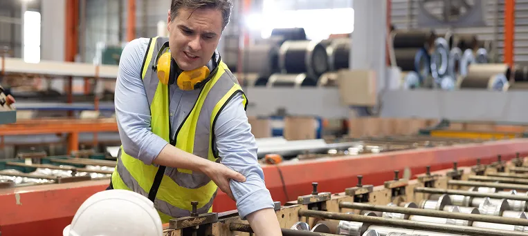 Factory worker suffering arm injury while operating equipment, highlighting workplace accident claims handled by workers compensation lawyers in California.