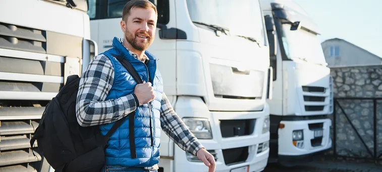 Truck driver standing near commercial trucks representing employees protected by workers compensation law and assisted by workers compensation attorney in California.
