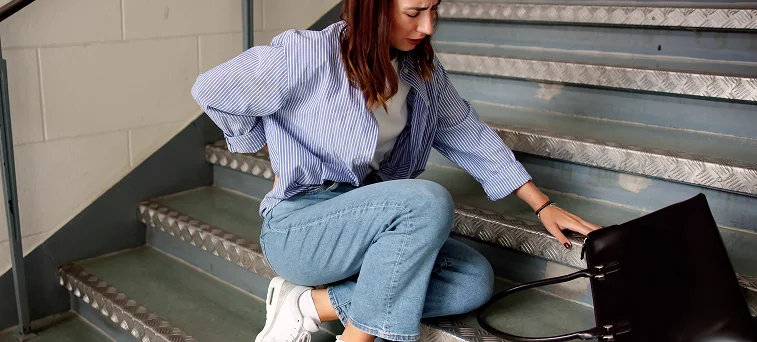Injured woman sitting on staircase holding lower back after slip accident highlighting claims handled by slip and fall lawyer Los Angeles.